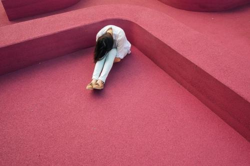 woman sitting sad pink background